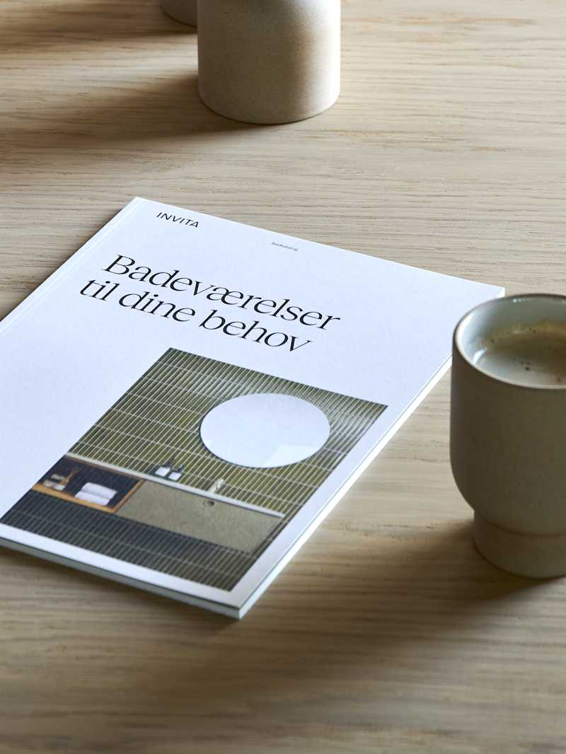 Træbord i INVITAs butik med kaffekopper og katalog