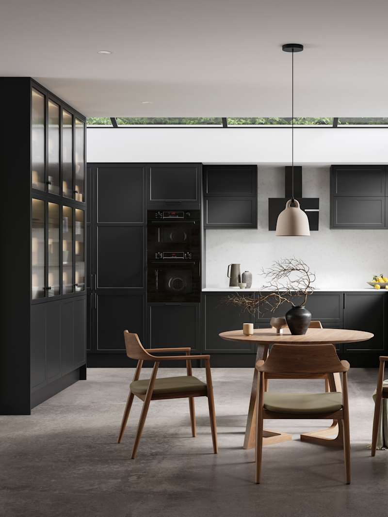 Modern Shaker kitchen Brunswick Sumi Black handleless with integrated ovens in tall cabinetry, open layout living room with wood dining table, hallway cabinetry with coat hangers and akupanel.