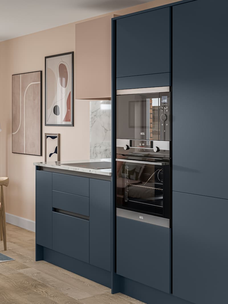 Handleless Integra Ascoli Mineral Blue, a dark blue kitchen with built-in ovens in tall cabinetry, an induction hob in white and grey marbled worktop with matching upstand.