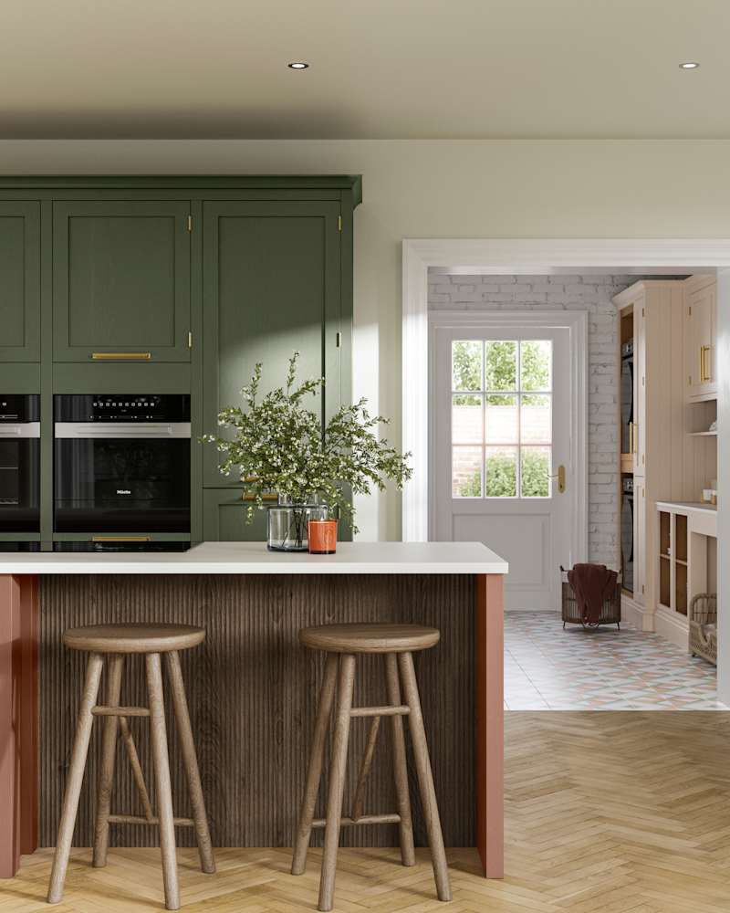 Tall Wardley kitchen cabinets  with built-in ovens, a kitchen island in shade Clay with wooden panelling by seating area and matching wooden bar stools.