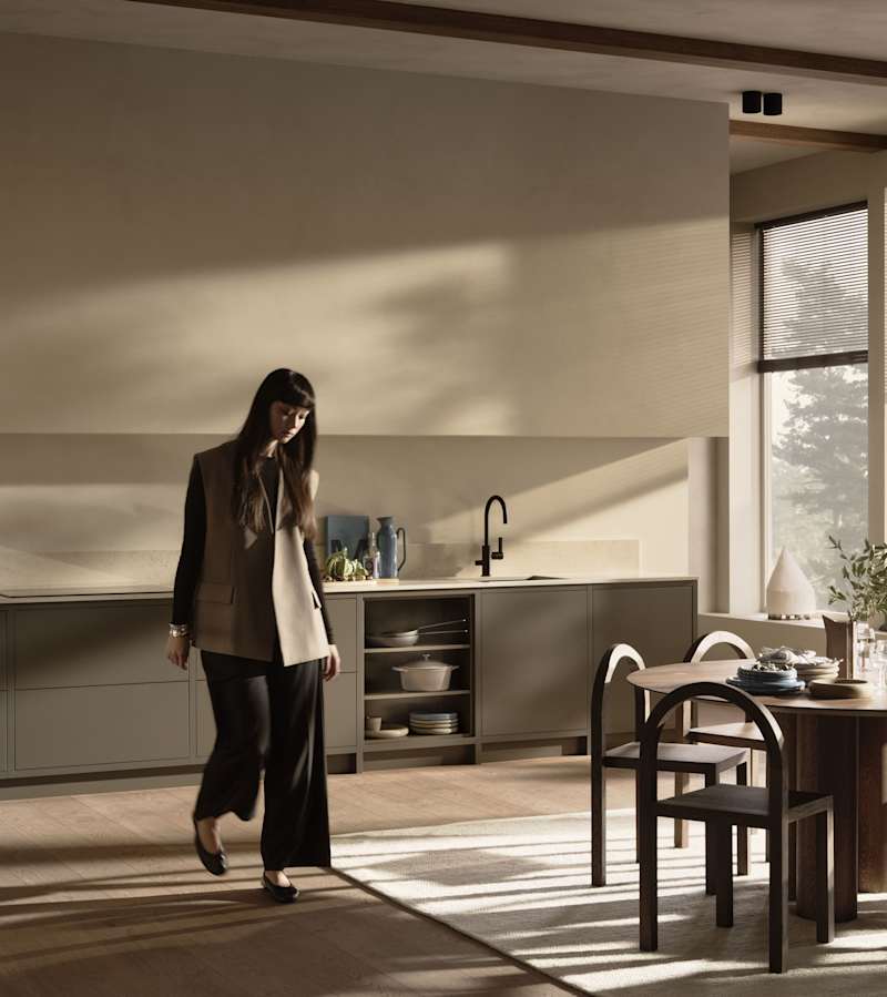 En kvinna går genom ett Warm Minimalism-kök från Marbodal.
