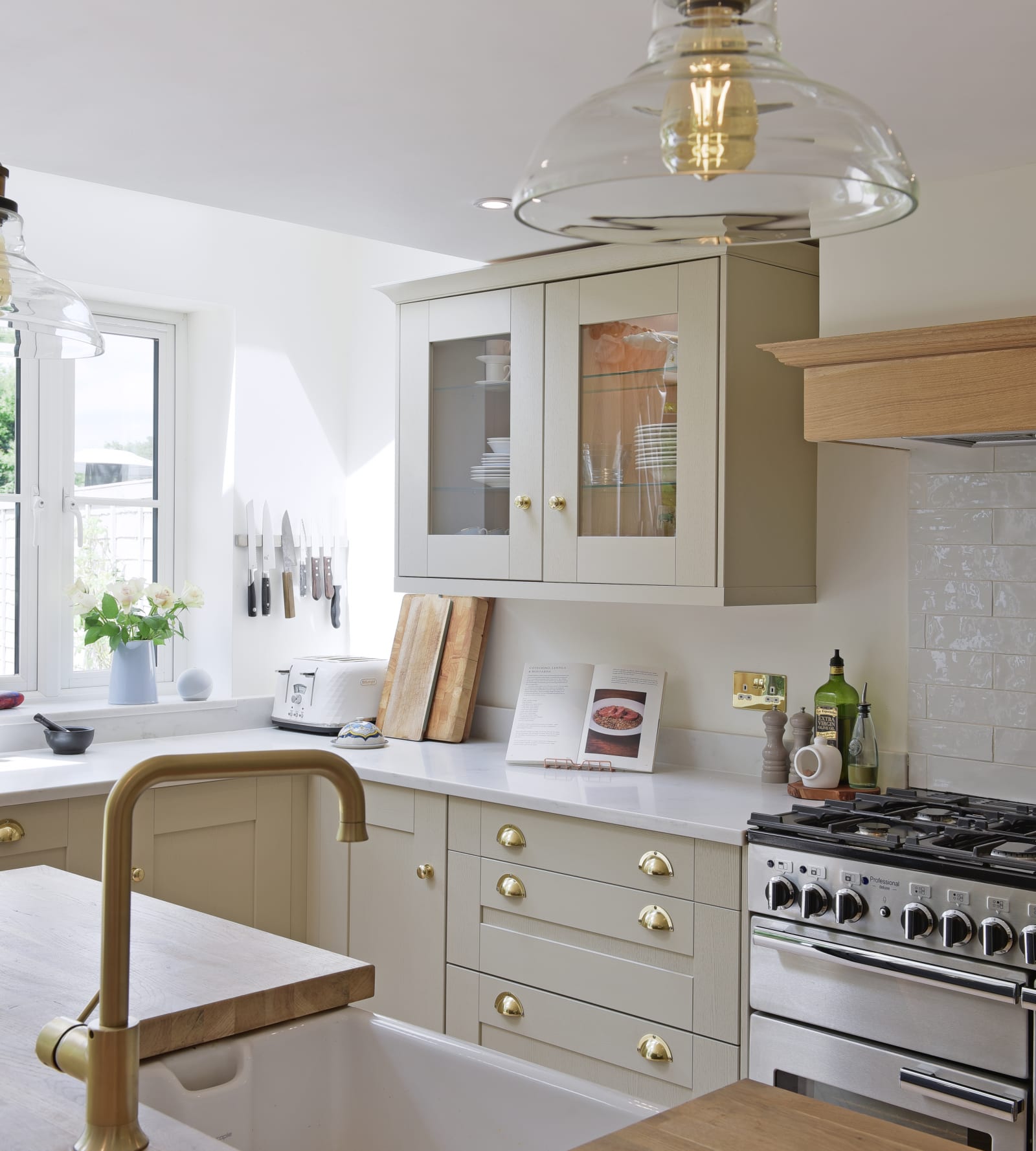 View over the sink, of the stove and display cabinets with glass doors in sage wooden frames.