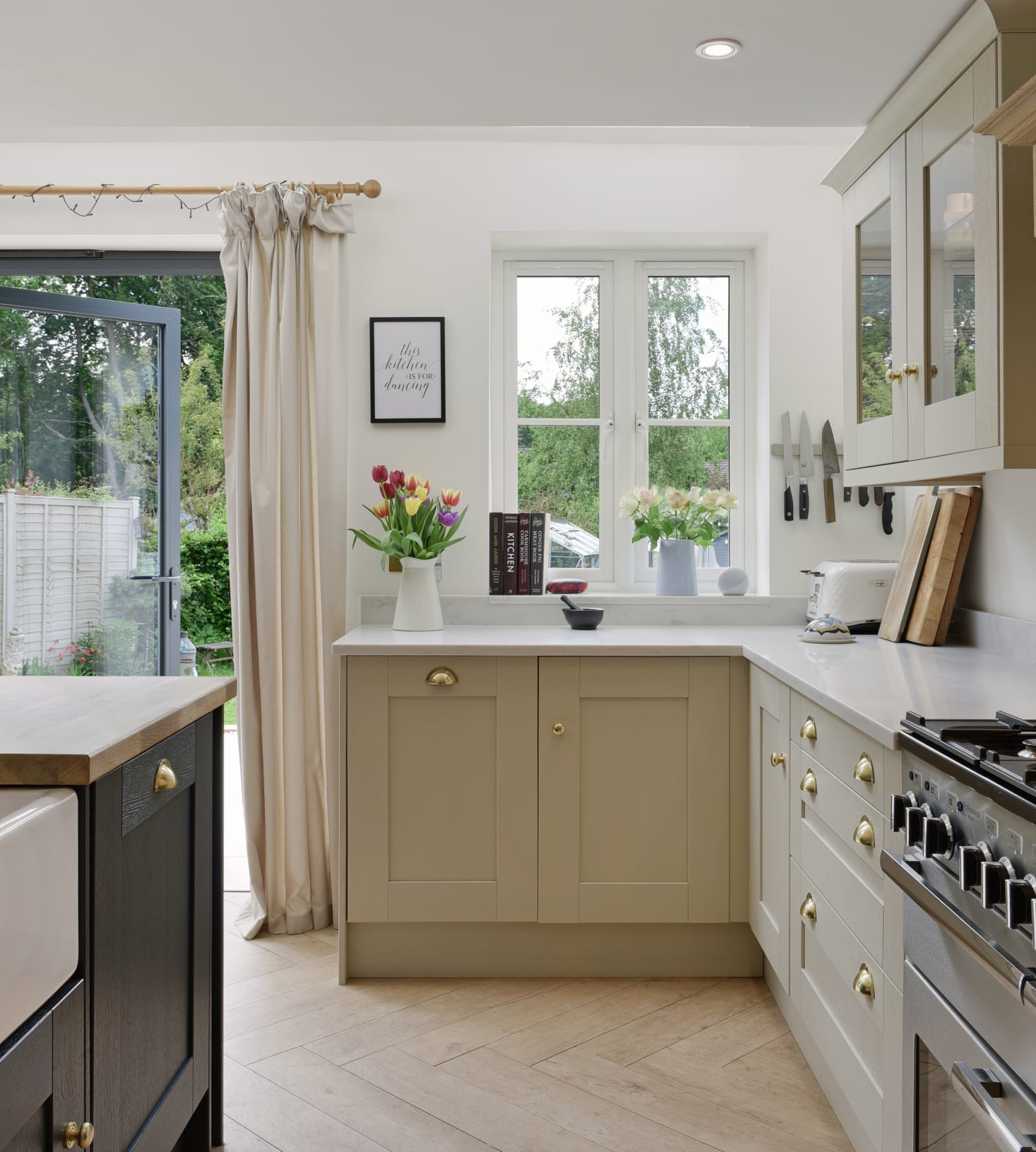 Parallell view of the stove and kitchen island, with windows to a garden above the counter.