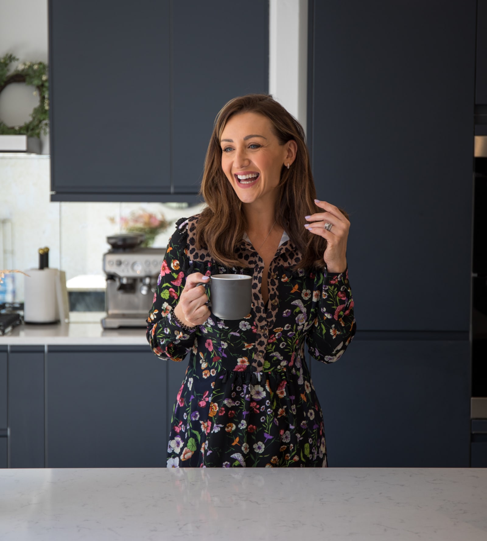 Cath Tyldesley laughing and holding a cup in her chic and contemporary handleless Luna Midnight kitchen from Magnet.