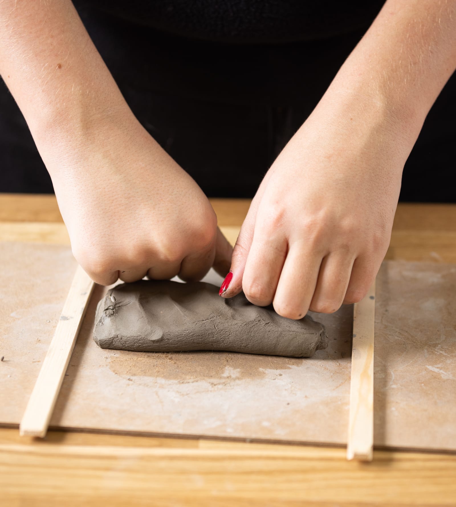 Close-up of hands forming clay on a wooden tray