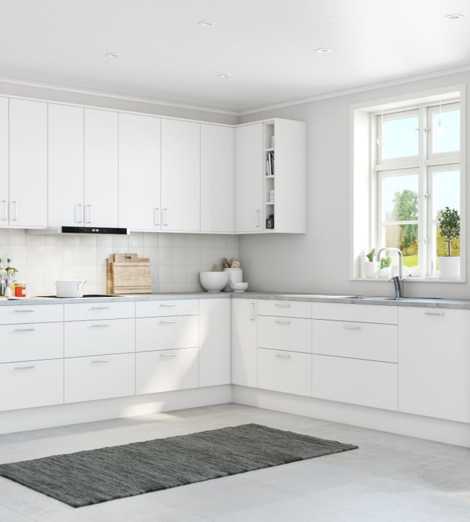 Köket Aspö från Marbodal, ett vitt kök med släta luckor och raka rena linjer, högskåp med integrerade ugnar och bänkskiva i grå laminat.