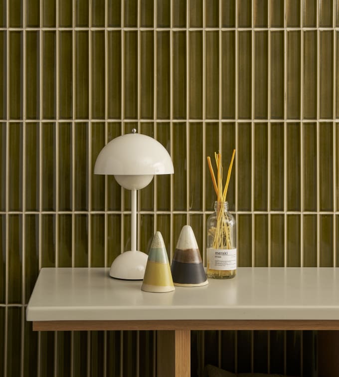 Nærbillede av eg hylder i Jubilæumsbad fra INVITA med grønne skaber inspireret av 1970'erne og grønne fliser