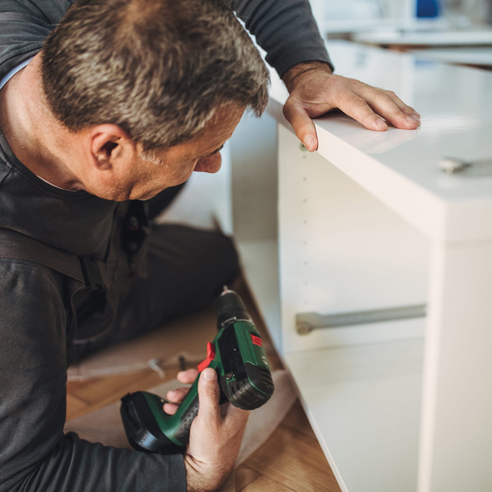 A man assembling a cabinet with a screwdriver