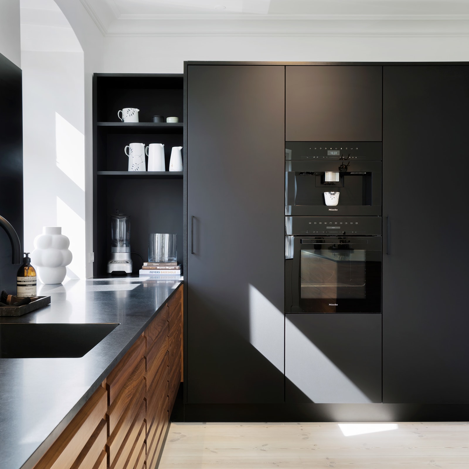 Tall cabinets in matt black laminate with built-in coffee machine and oven