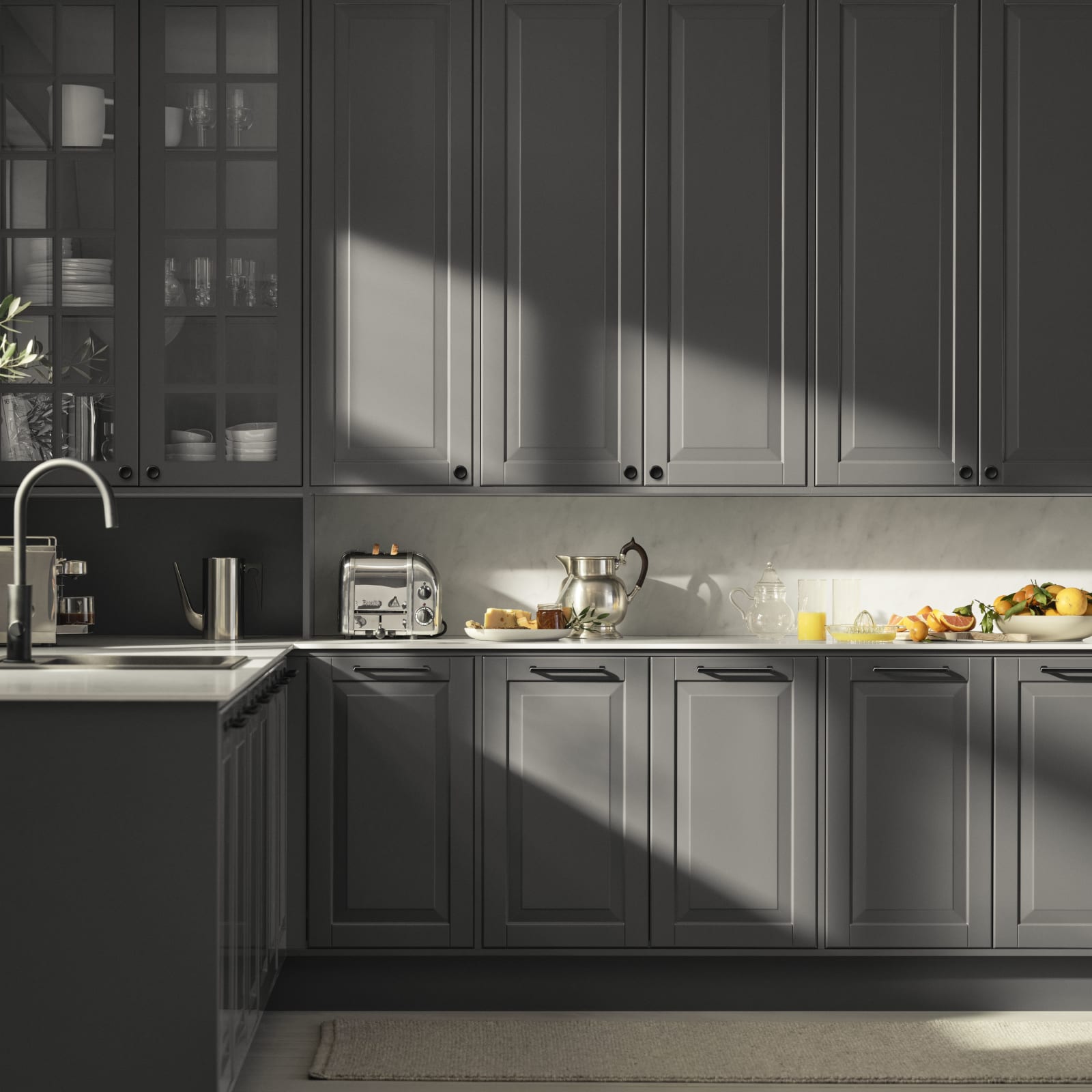 Mørk grå landkøkken Nordic Granit fra INVITA med fyldningslåger, sort håndtag, vitrineskab med sprosselåger og hvid marmor laminatbordplade
