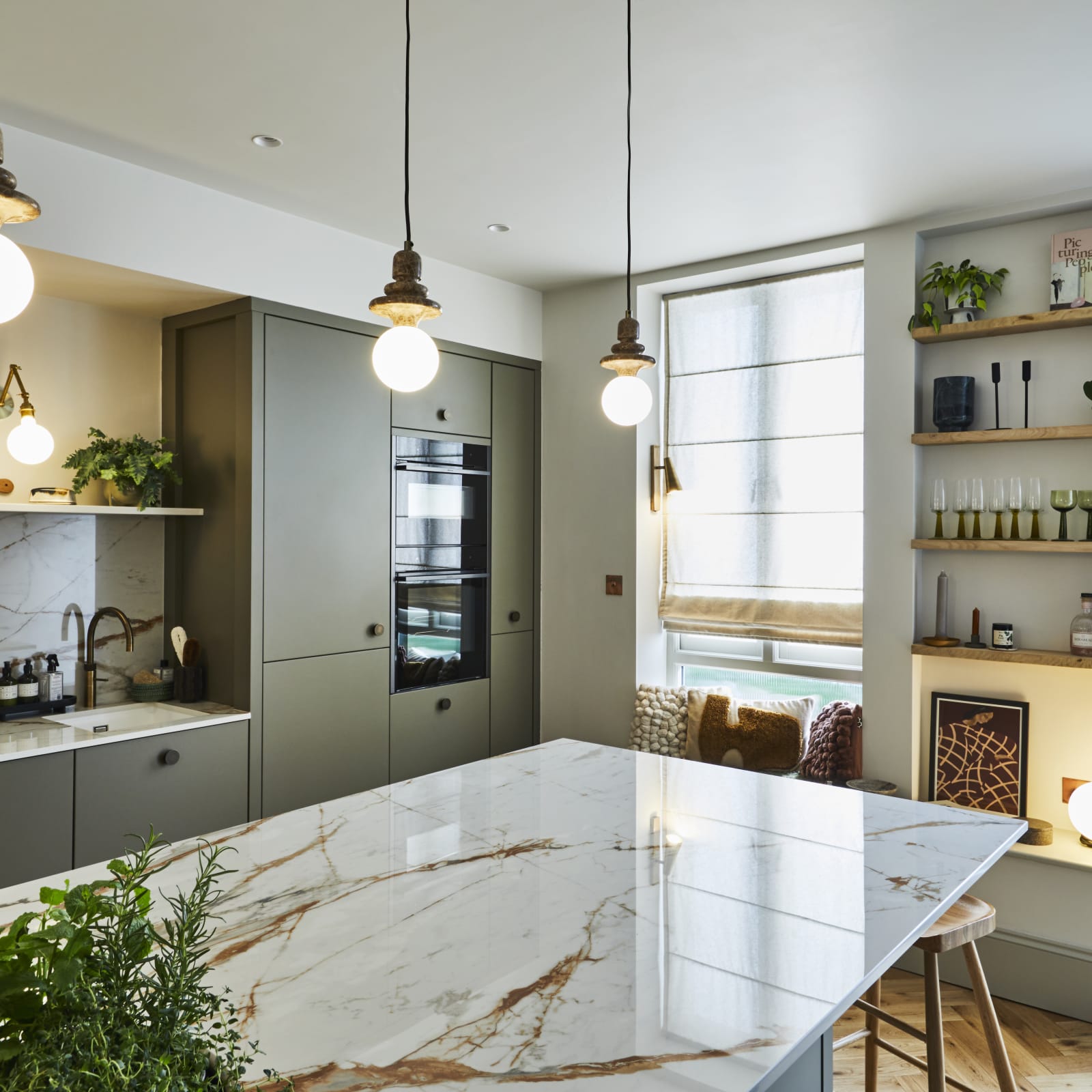 View over kitchen island of modern slab Soho cabinets in the Balmoral colour, a soft beige green tone