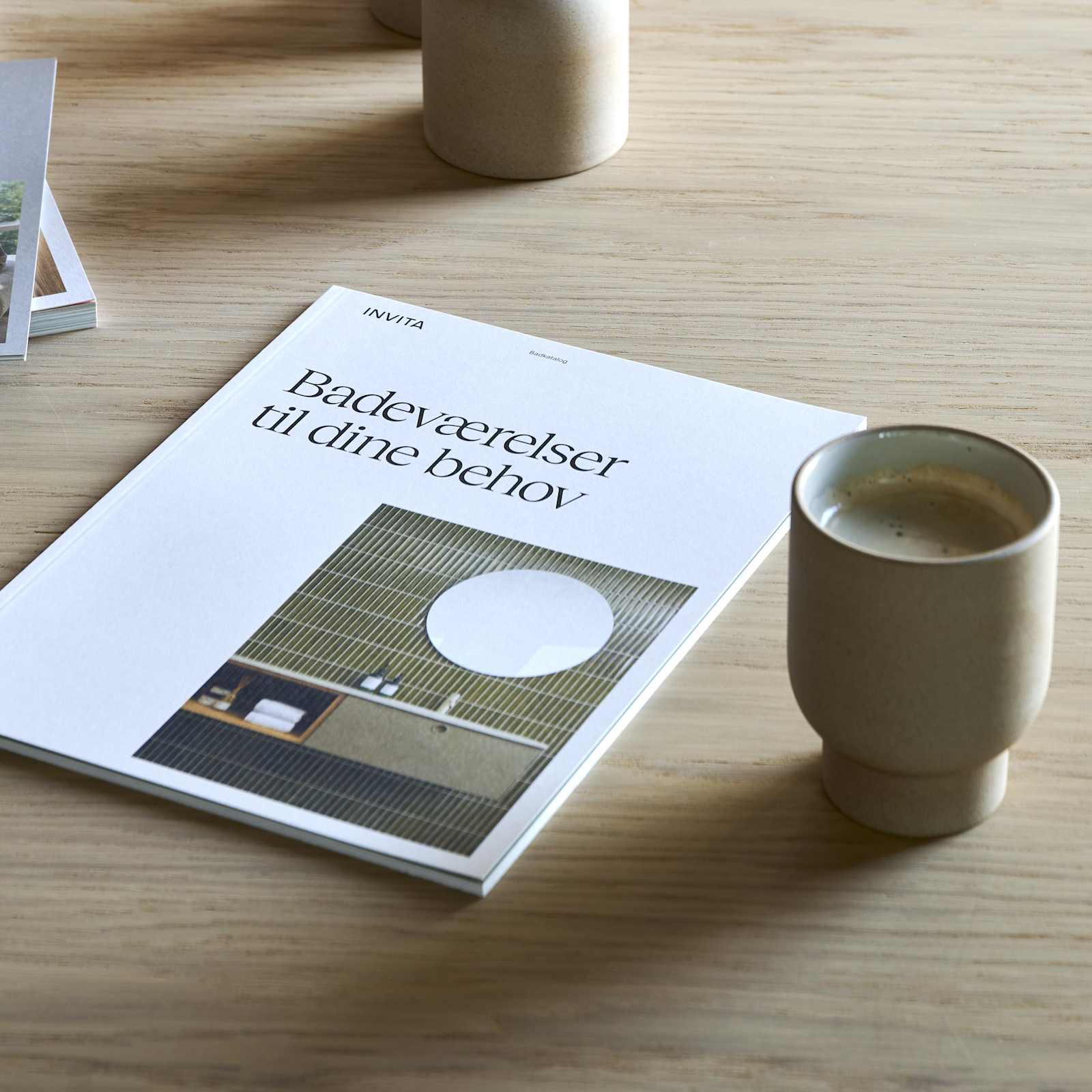 Træbord i INVITAs butik med kaffekopper og katalog