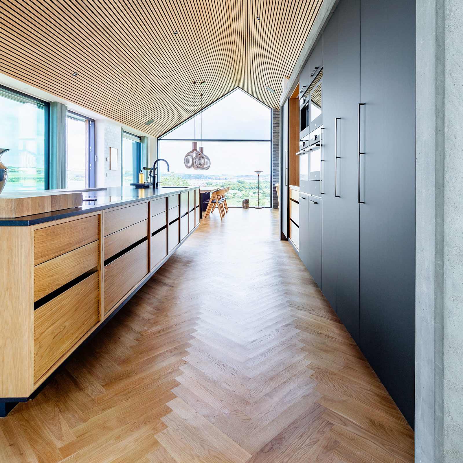 Stor Copenhagen køkkenø i egetræ og højskabe i matsort laminat fra uno form