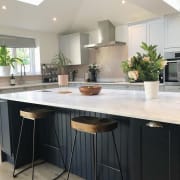 View of the dark blue Midnight kitchen island's bar stool seating area with Carrara White worktop and the matching Dunham cabinetry in Dove Grey.