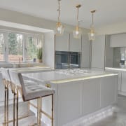 The Waugh family's stunning feminine 1920s Art Deco style kitchen, the Integra Dunham Dove Grey from Magnet, with a kitchen island paired with matching barstools.