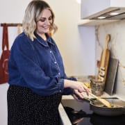 Jen stirring in a pan on the stove and smiling