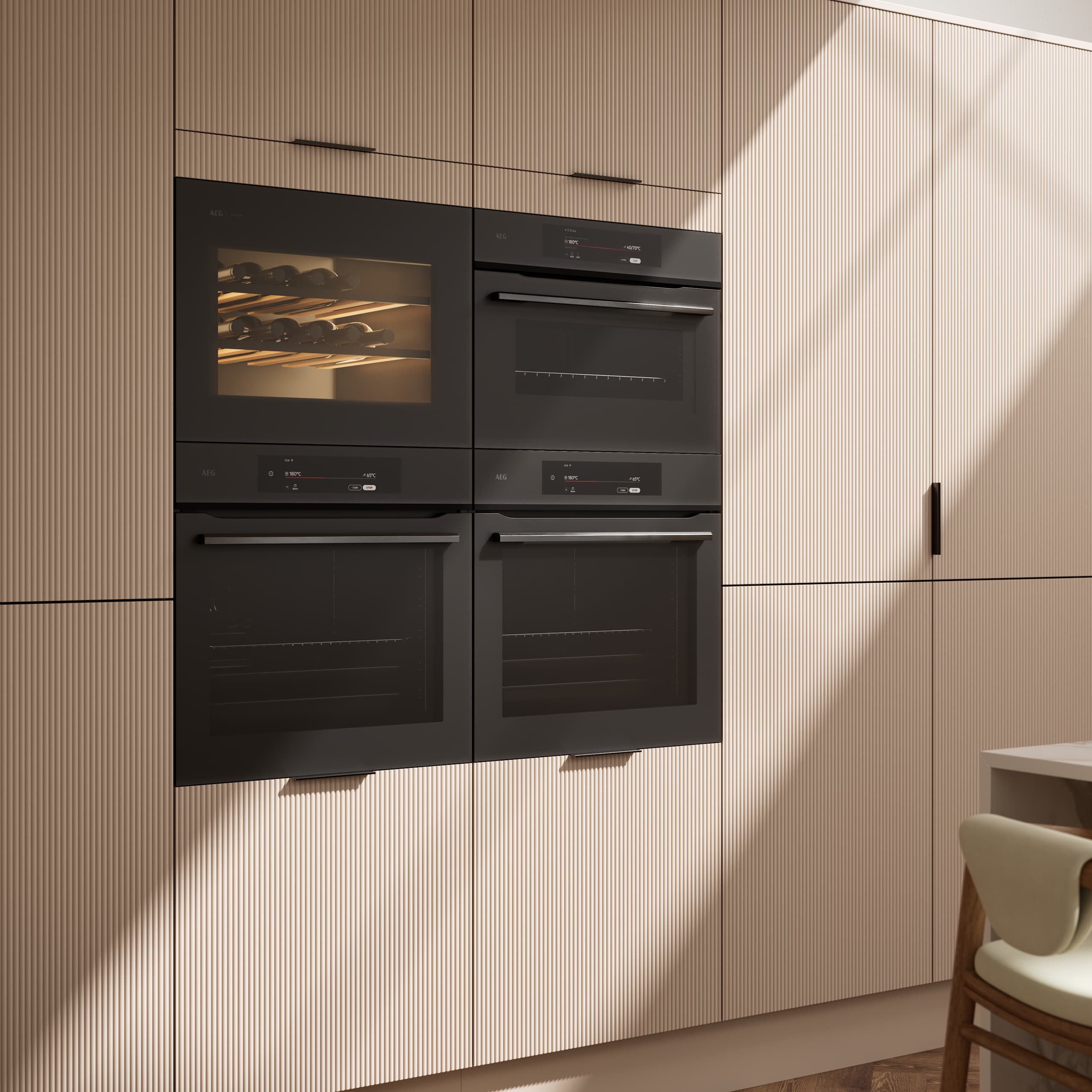 Fluted front kitchen Reed from Magnet in light warm neutral shade Shell, tall cabinets with appliances like ovens and a wine cooler, black handles