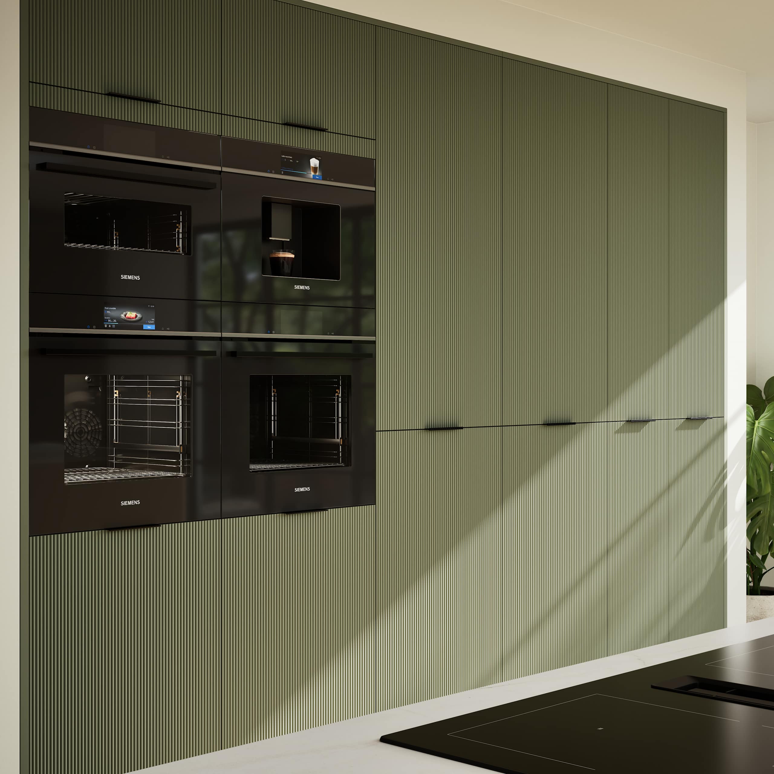 Green fluted kitchen fronts on tall cabinets with built-in appliances and black handles.