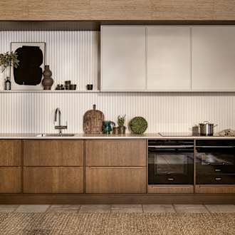 Mørk eg køkkenbænk Forever Oak fra INVITA kombineret med overskaber Athena Sand, hvide fliser, bordplade og massiv ek håndtag, ovn og dampovn fra Siemens