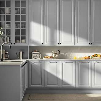 Lys grå landkøkken Nordic Sky fra INVITA med fyldningslåger, sort håndtag, vitrineskab med sprosselåger og hvid marmor laminatbordplade