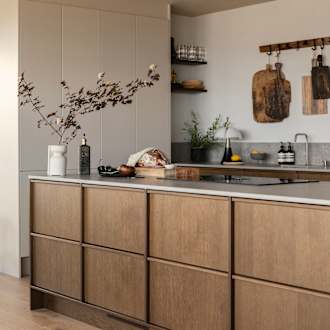 Køkkenø i brun egetræsfiner køkkenet Contours med matchende tre håndtag fra INVITA med beige højskabe Athena Sand