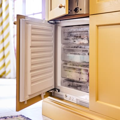 Opened integrated freezer in Ludlow Harvest cabinetry, fronts in a traditional Shaker style with tactile woodgrain, from Magnet.