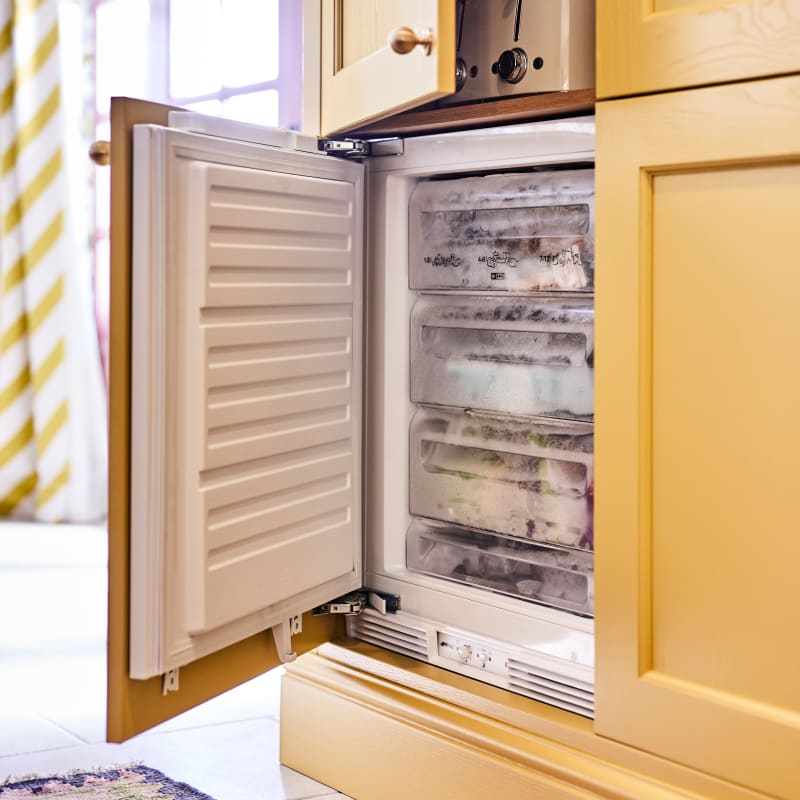 Opened integrated freezer in Ludlow Harvest cabinetry, fronts in a traditional Shaker style with tactile woodgrain, from Magnet.