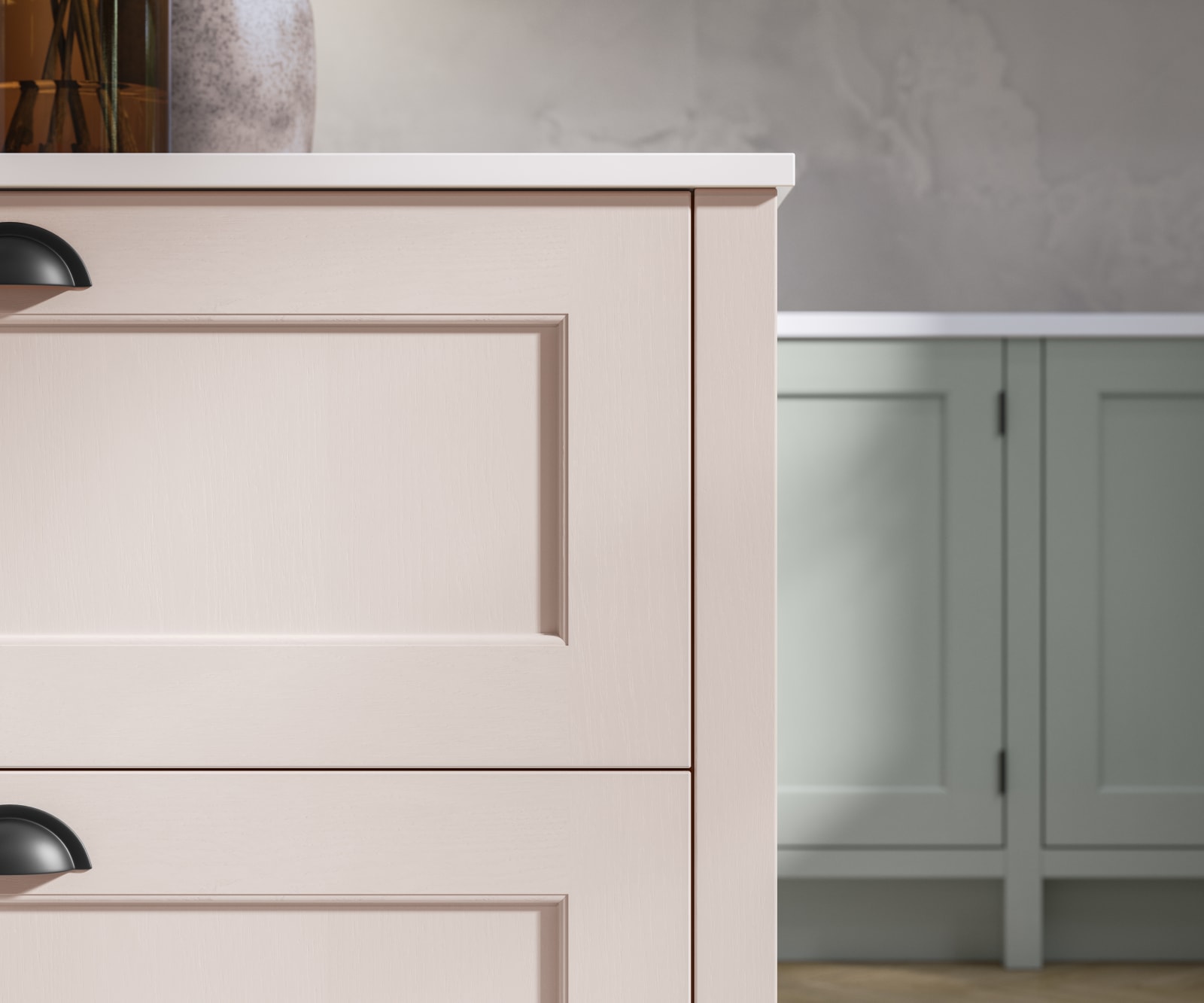 Closeup of Ludlow kitchen island, in a light pink colour with black accent handles.