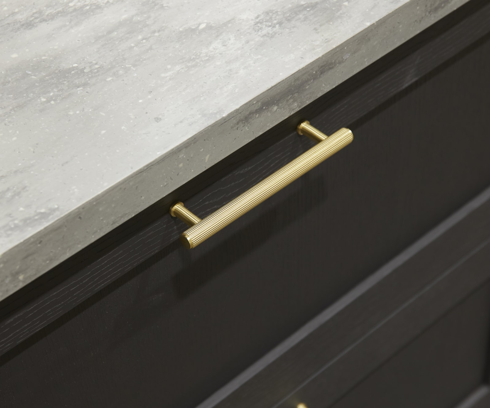 A close-up view of Ambleside drawer frontals in Graphite, with brass bar handles and grey worktop.