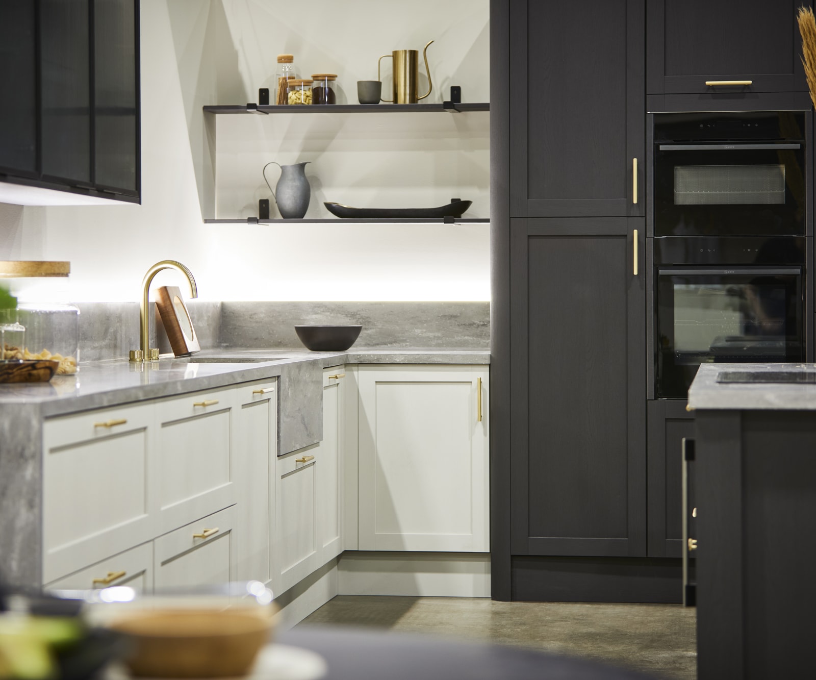 The Ambleside kitchen in Limestone and Graphite, paired with brass bar handles, a grey worktop and modern brass tap.
