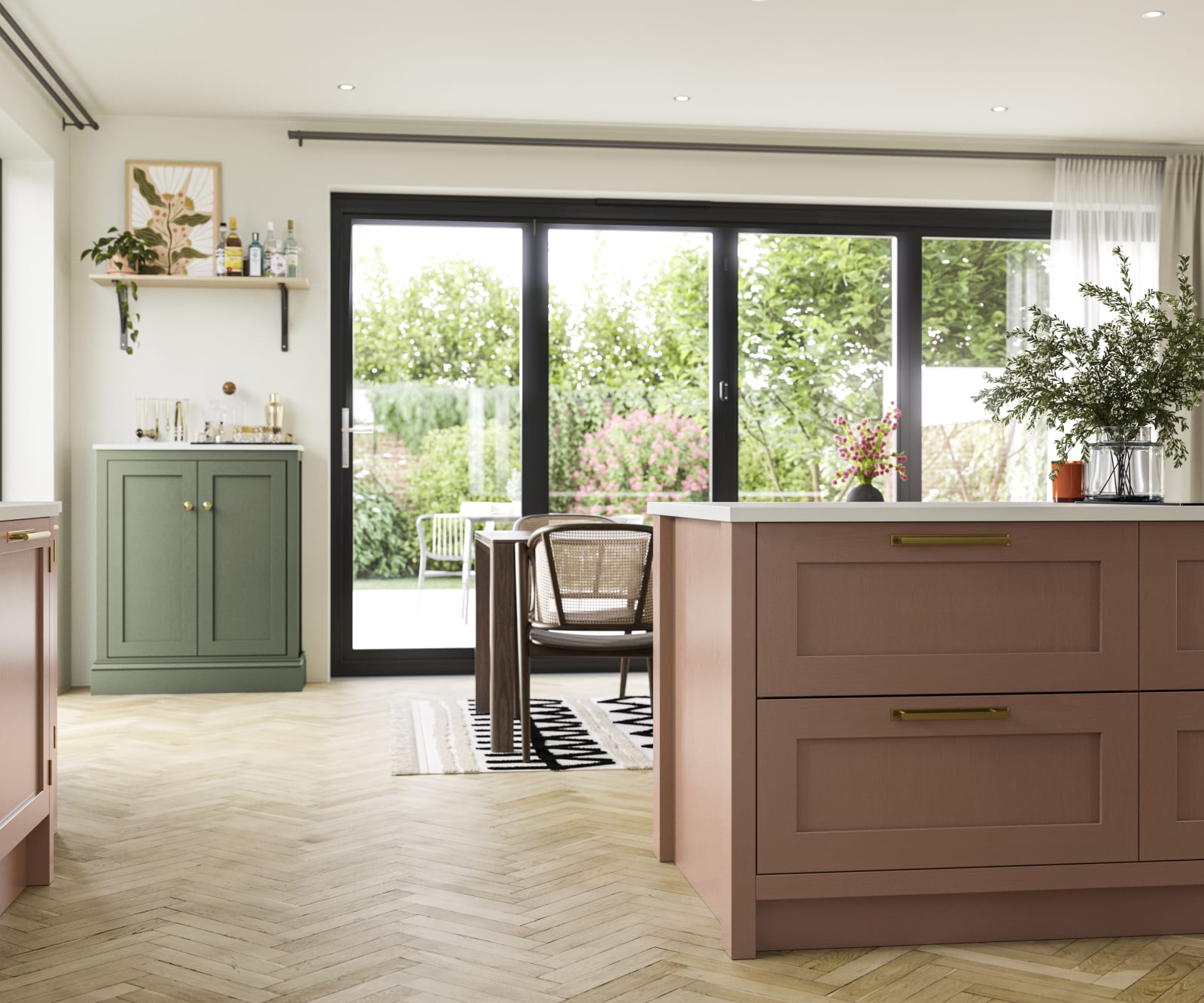 Wardley cabinetry in open floorplan kitchen and dining room with kichen island in shade Clay and a sideboard cabinet in shade Thyme, glass doors showing garden outside.