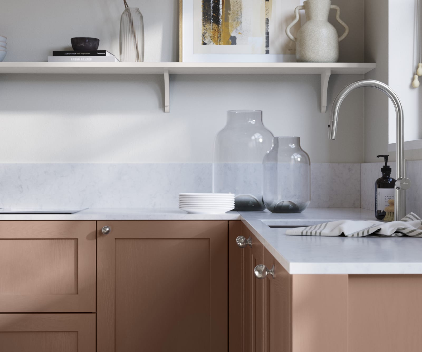 Wardley Clay kitchen cabinetry with steel knobs, steel tap, white marbled worktop and matching backsplash. An open shelf on the wall above cabinets with ceramics and a vase of flowers.