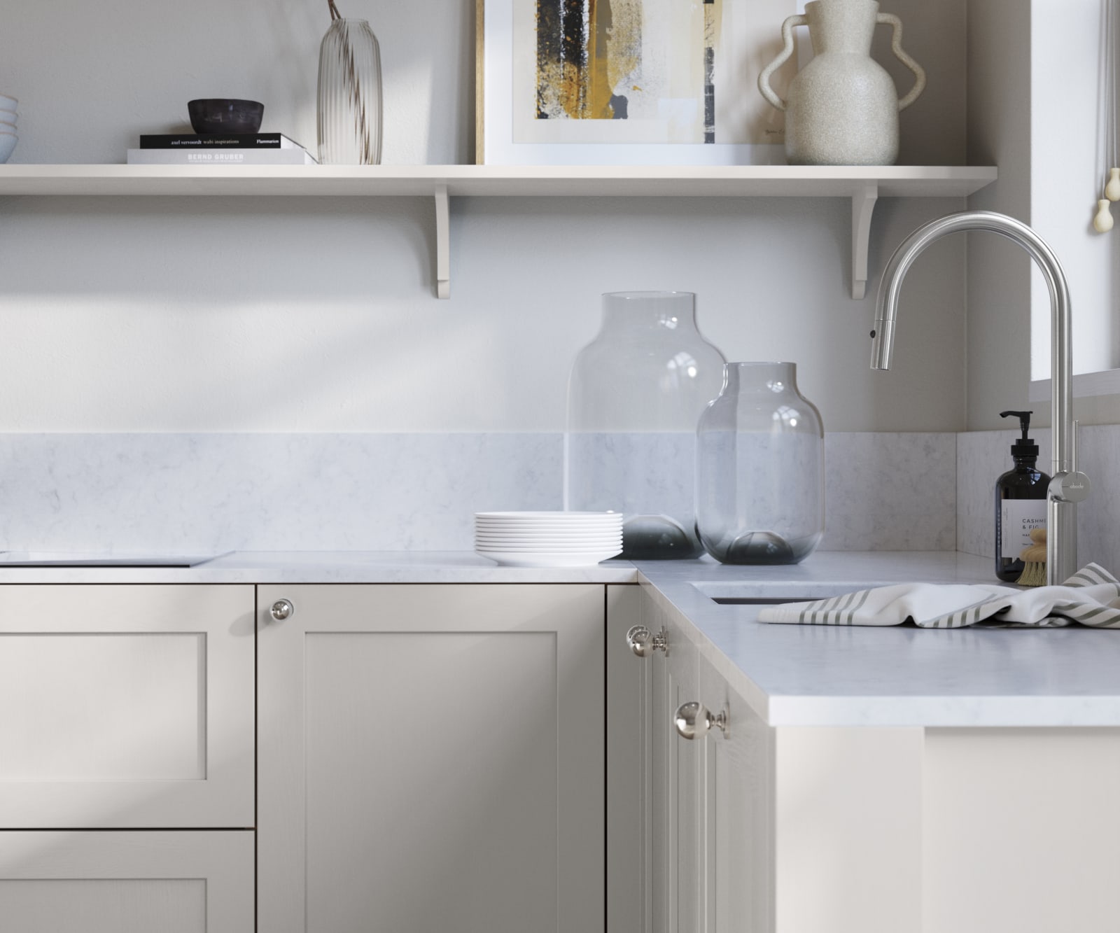 Wardley Fresh Linen kitchen cabinetry with steel knobs, steel tap, white marbled worktop and matching backsplash. An open shelf on the wall above cabinets with ceramics and a vase of flowers.