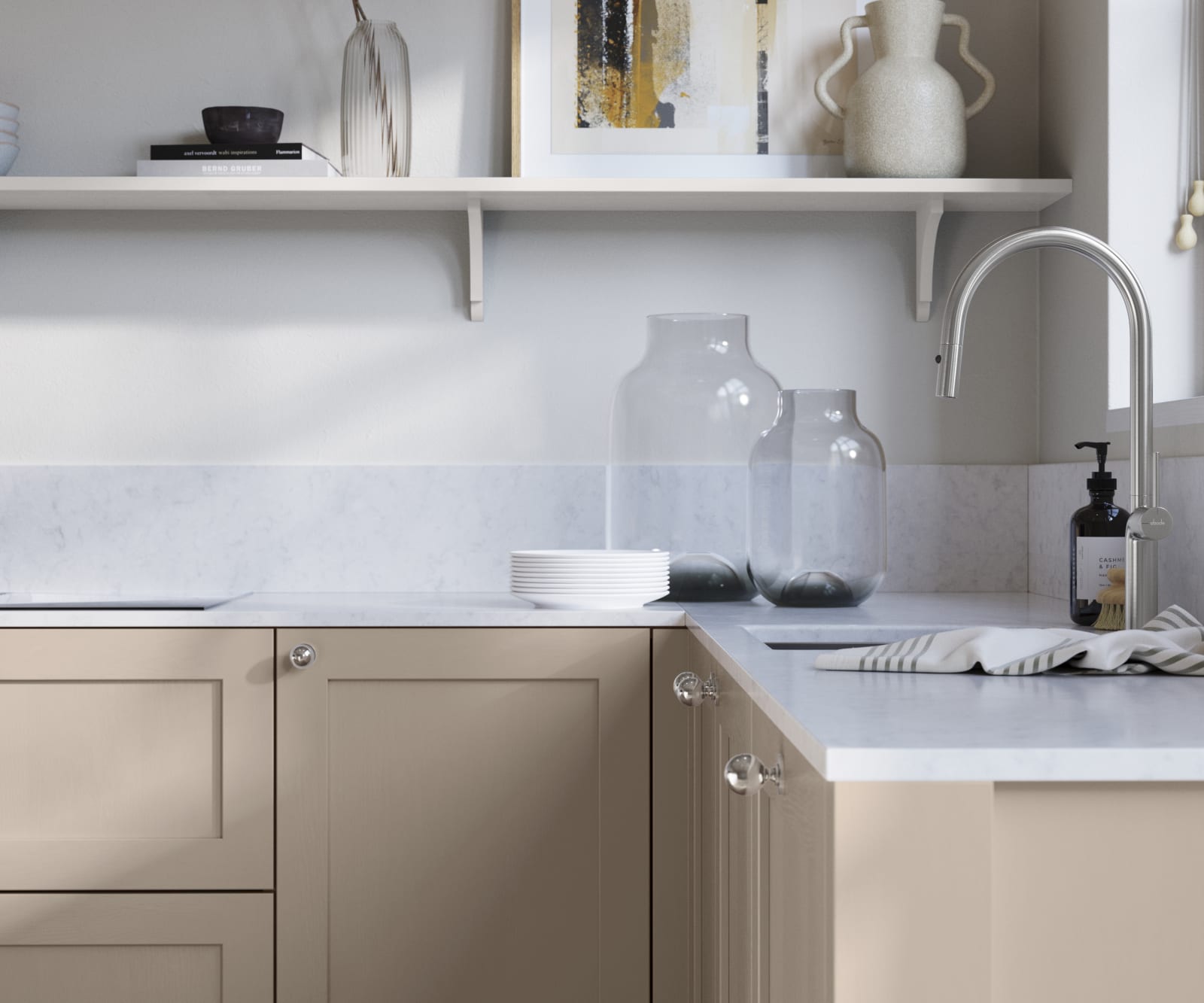 Wardley Shell kitchen cabinetry with steel knobs, steel tap, white marbled worktop and matching backsplash. An open shelf on the wall above cabinets with ceramics and a vase of flowers.