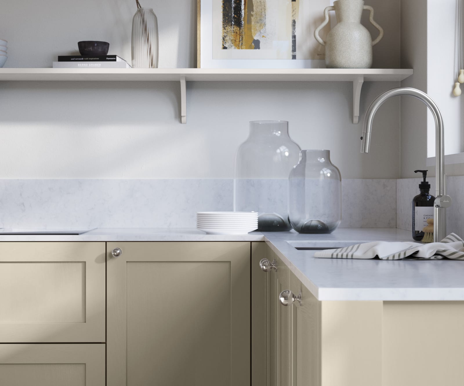 Wardley Pebble path kitchen cabinetry with steel knobs, steel tap, white marbled worktop and matching backsplash. An open shelf on the wall above cabinets with ceramics and a vase of flowers.