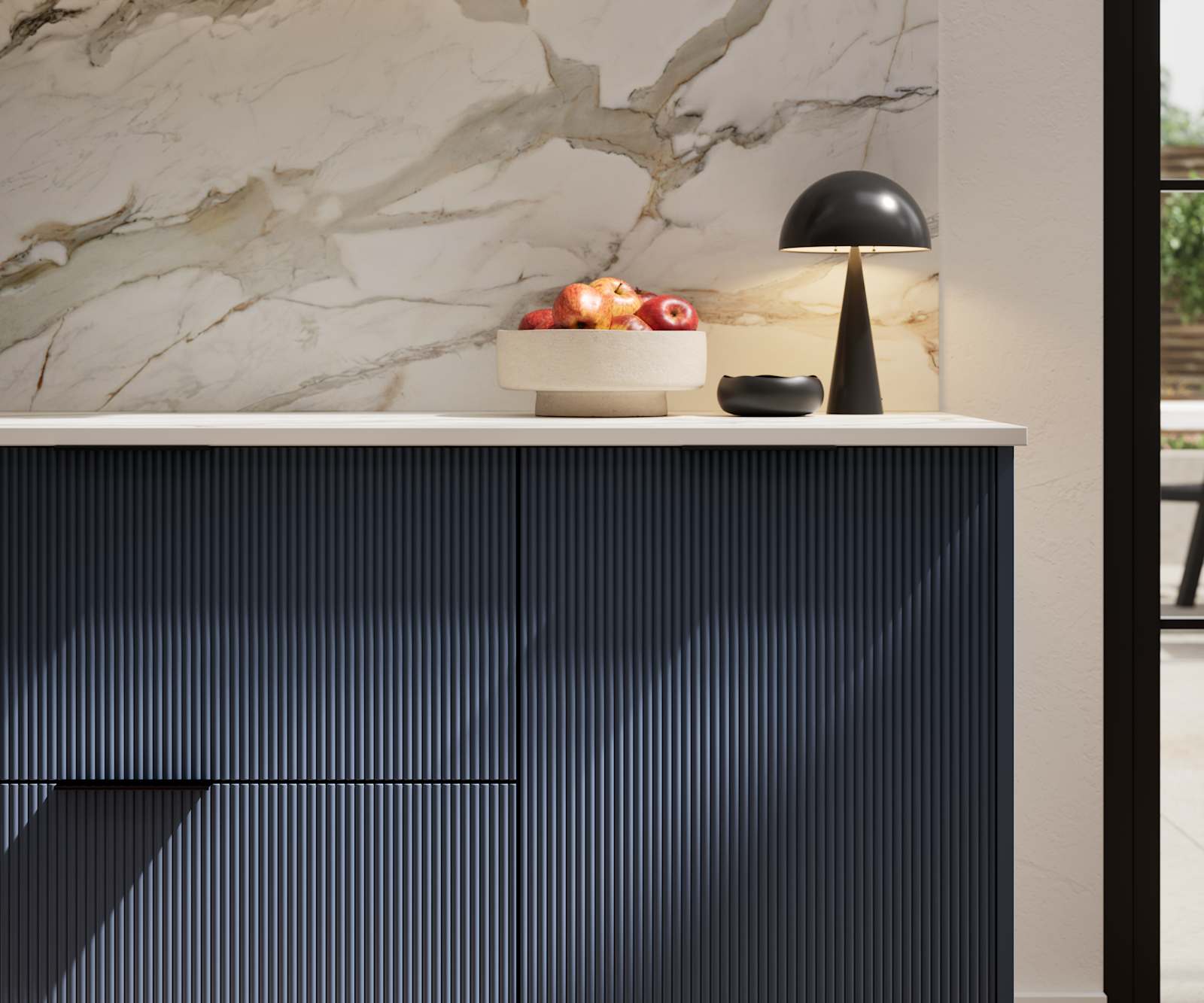 Fluted front kitchen Reed from Magnet in dark blue shade Midnight, with a marbled splashback and black handles, herringbone wood flooring.