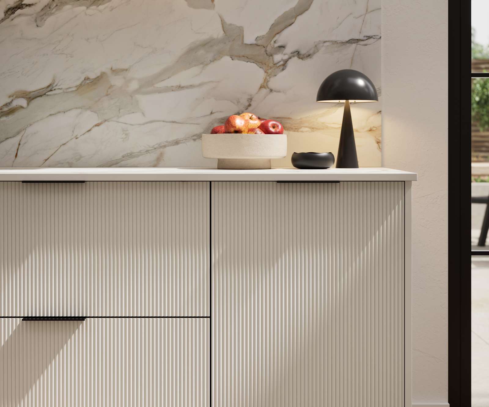 Fluted front kitchen Reed from Magnet in light neutral shade Limestone, with a marbled splashback and black handles, herringbone wood flooring.