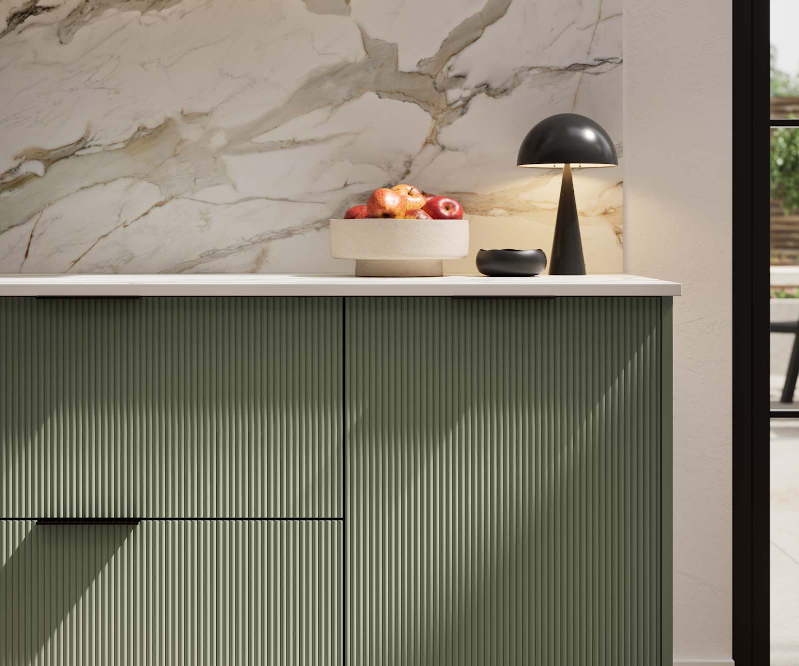 Fluted front kitchen Reed from Magnet in rich dark green shade Thyme, with a marbled splashback and black handles, herringbone wood flooring.