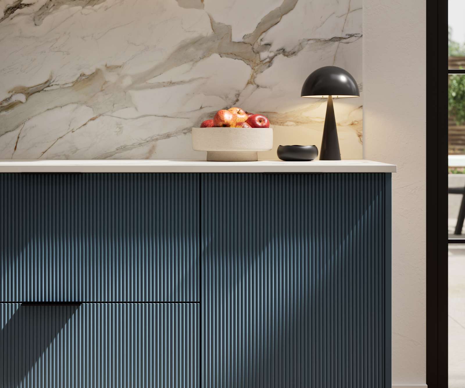 Fluted front kitchen Reed from Magnet in dark blue shade Voyage Blue, with a marbled splashback and black handles, herringbone wood flooring.