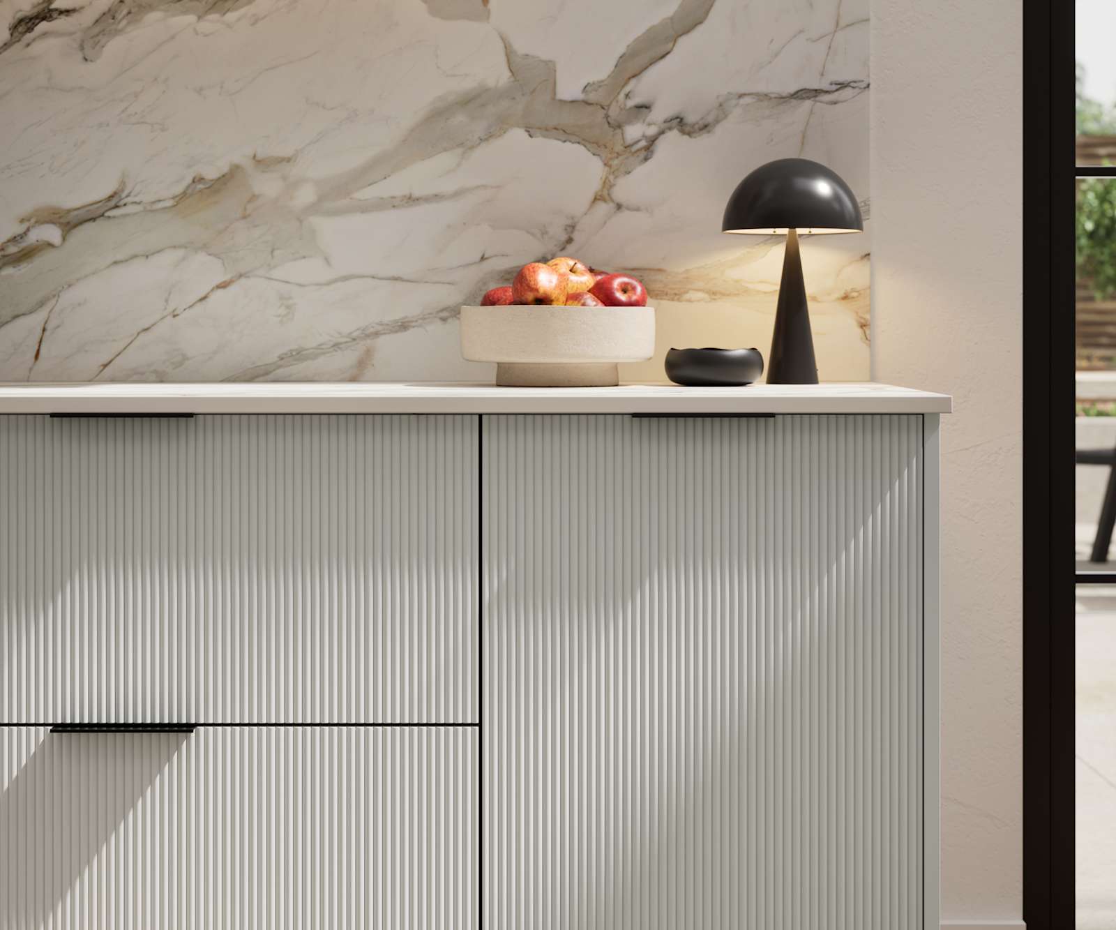 Fluted front kitchen Reed from Magnet in light neutral shade Washed cotton, with a marbled splashback and black handles, herringbone wood flooring.