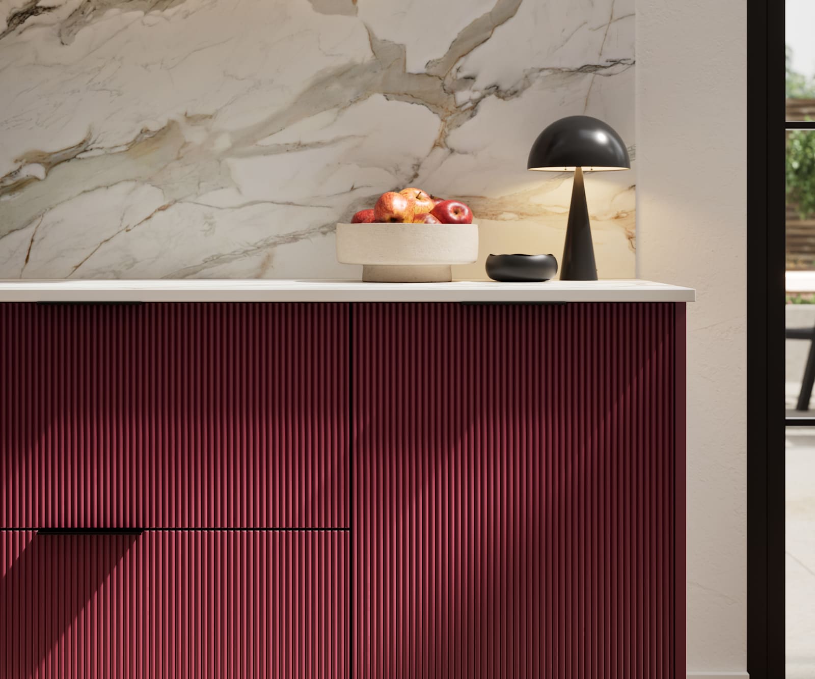 Fluted front kitchen Reed from Magnet in red shade Morello, with a marbled splashback and black handles, herringbone wood flooring.