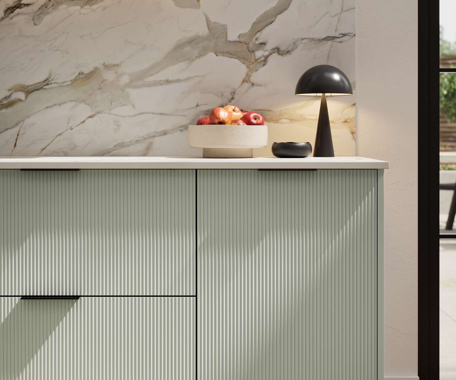 Fluted front kitchen Reed from Magnet in light green shade Seagrass, with a marbled splashback and black handles, herringbone wood flooring.