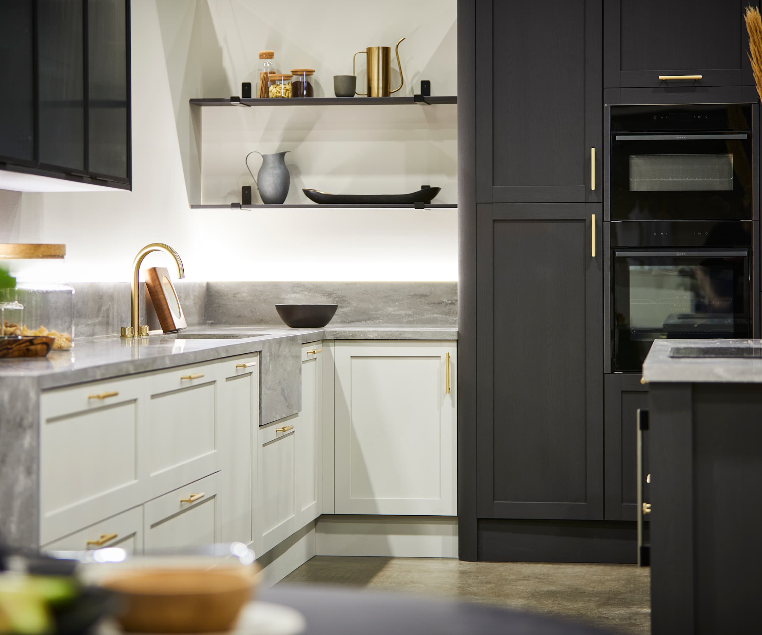 The Ambleside kitchen in Limestone and Graphite, paired with brass bar handles, a grey worktop and modern brass tap.