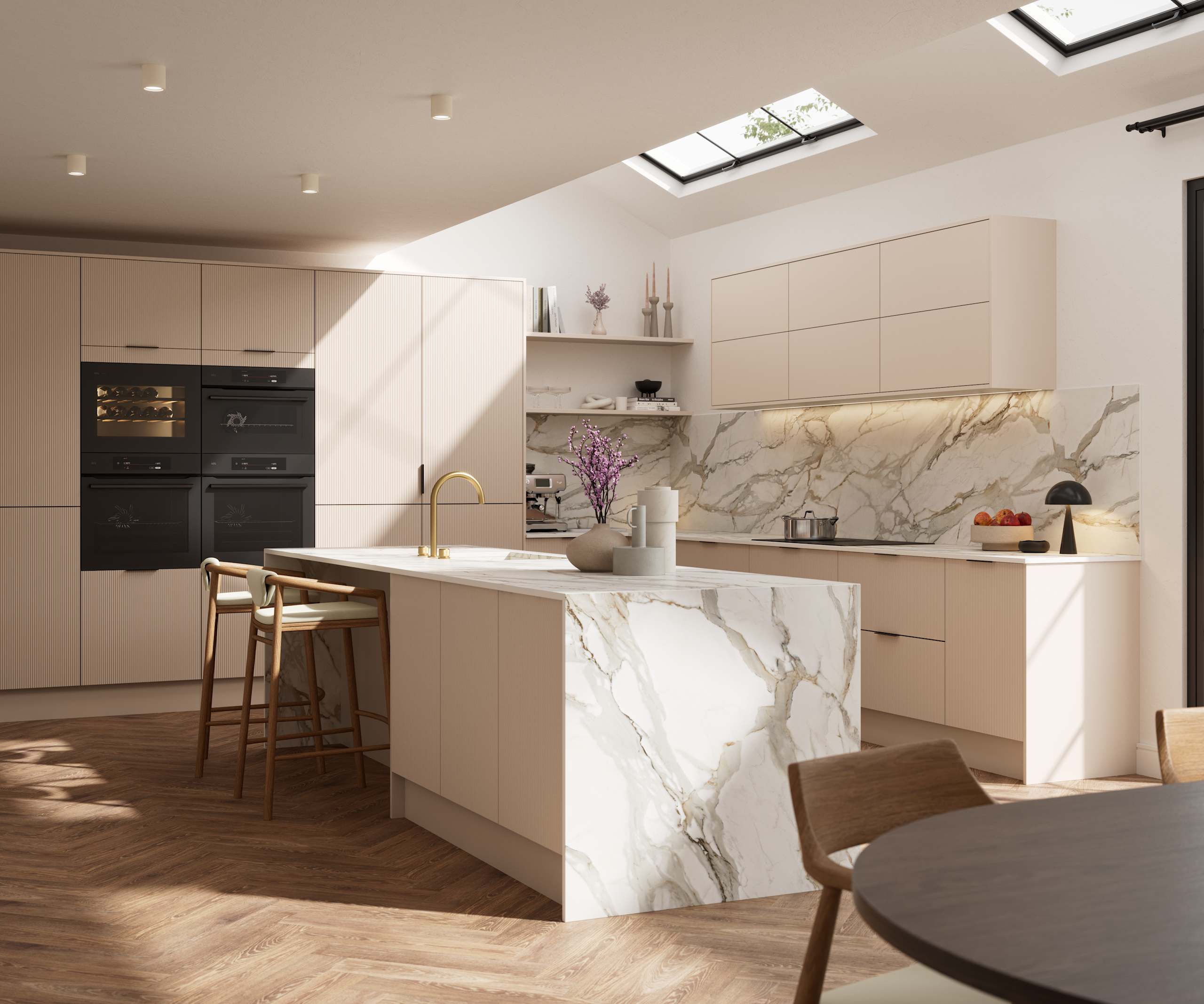 Fluted front kitchen Reed from Magnet in light warm neutral shade Shell, with a marbled splashback, worktop and decorative side on kitchen island with barstools and black handles, herringbone wood flooring.