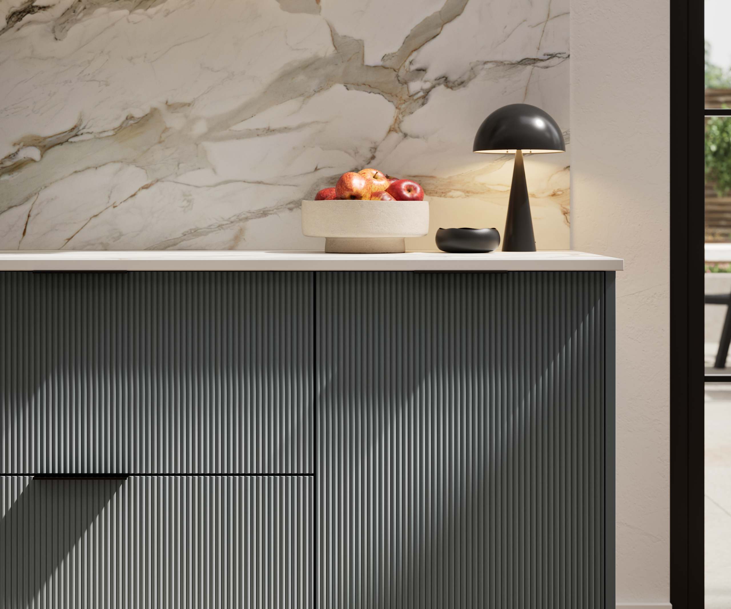 Fluted front kitchen Reed from Magnet in dark green shade Arboretum, with a marbled splashback and black handles, herringbone wood flooring.
