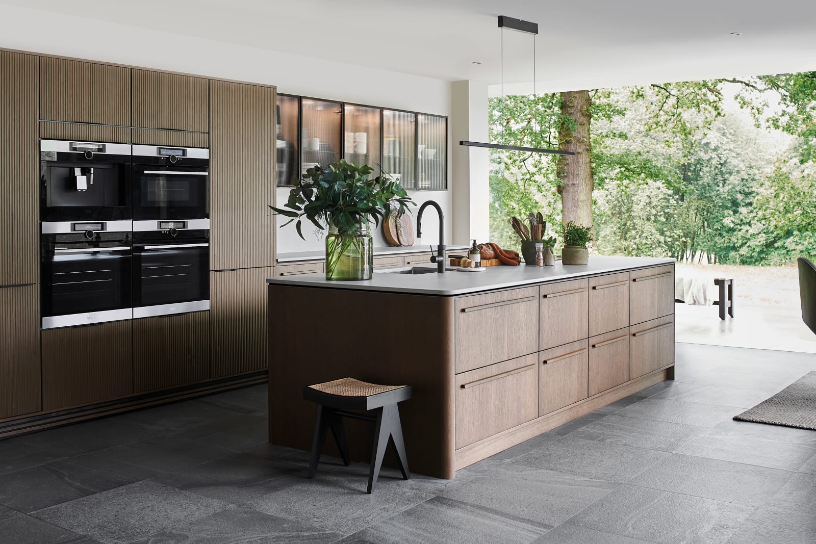 Magnet Kitchens 2021 Nordic Nature range with Fluted oak doors and Integra Hoxton Pebble cabinets with Dekton Aeri worktop. U-shaped kitchen with breakfast bar area.