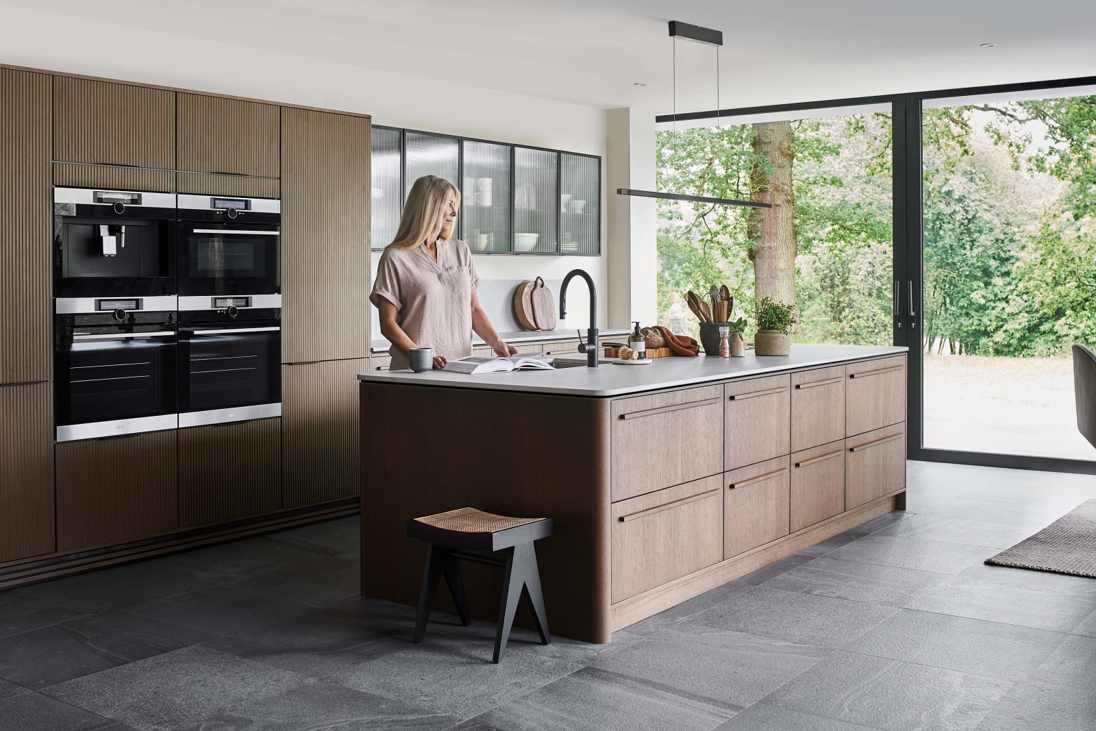 Open layout Nordic Nature oak kitchen from Magnet, with fluted glass vitrine doors on wall cabinets.