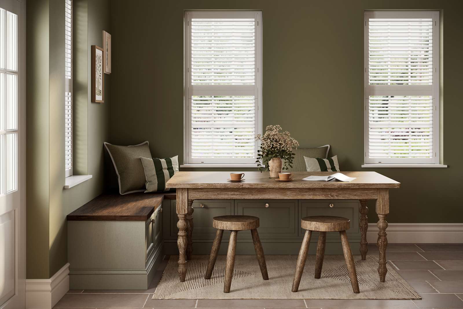 Dining area with low Shaker style painted wood grain cabinets Bewdley cabinets as a bench with a wooden table and stools in a room with painted green walls.