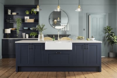 Modern country-style kitchen island with Shaker door Ludlow in dark blue shade Midnight, a porcelain sink, marbled worktop, brass tap and open shelves in matching blue.