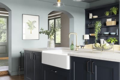 Modern country-style kitchen island with Shaker door Ludlow in dark blue shade Midnight, a porcelain sink, marbled worktop, brass tap and open shelves in matching blue.